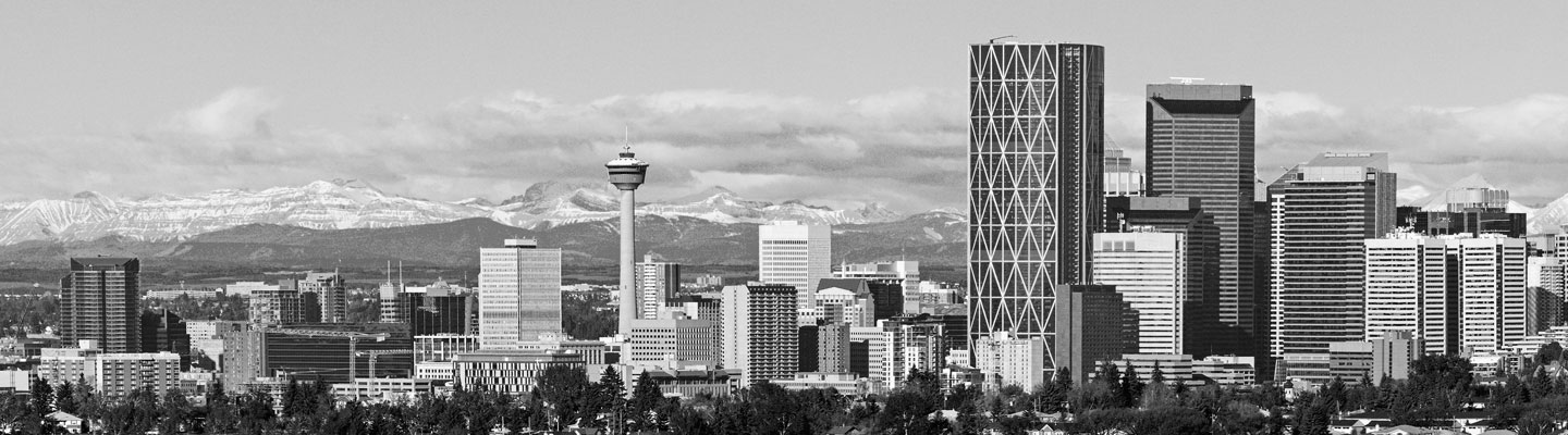 Downtown Calgary city core with large blue mountains far behind it