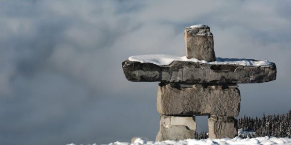 An inuksuk with snow-covered mountain tops in the background